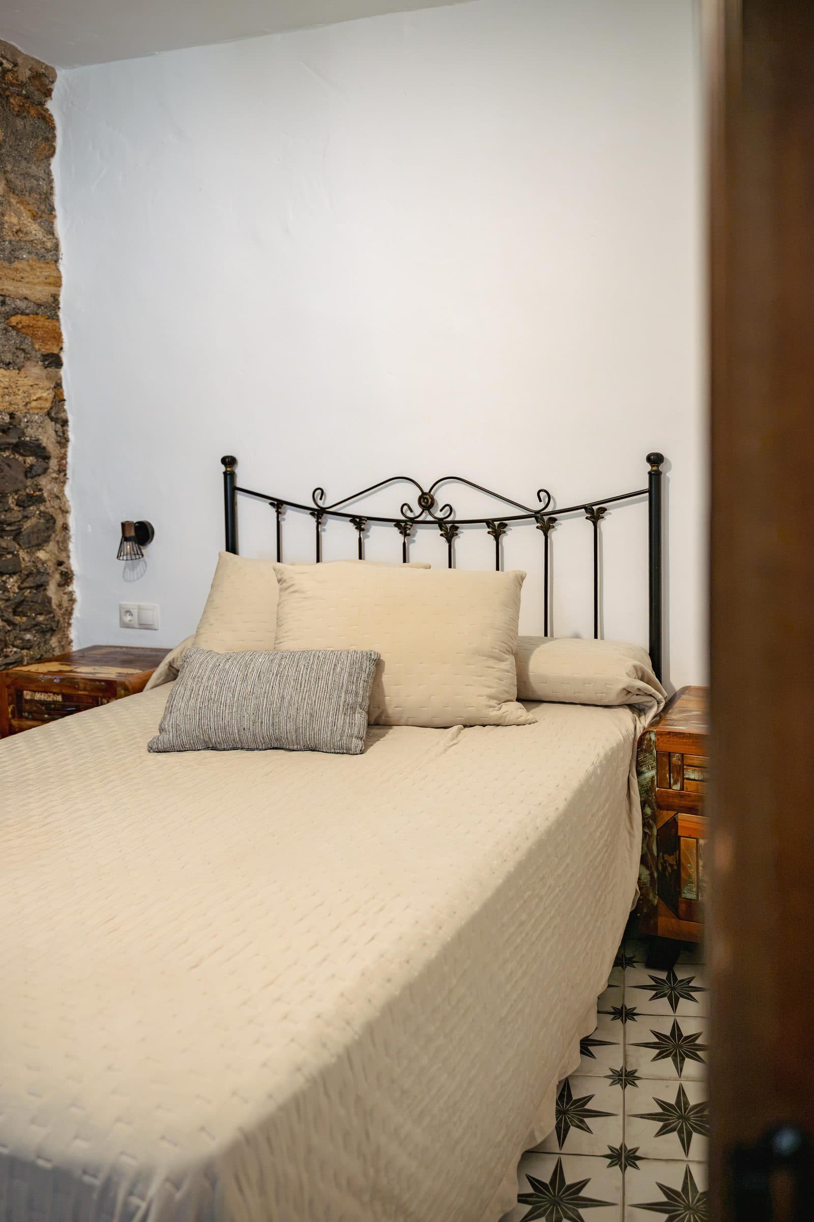 Dormitorio con cabecero de forja contra el muro de piedra, en Casa Cuadra, en Albondón