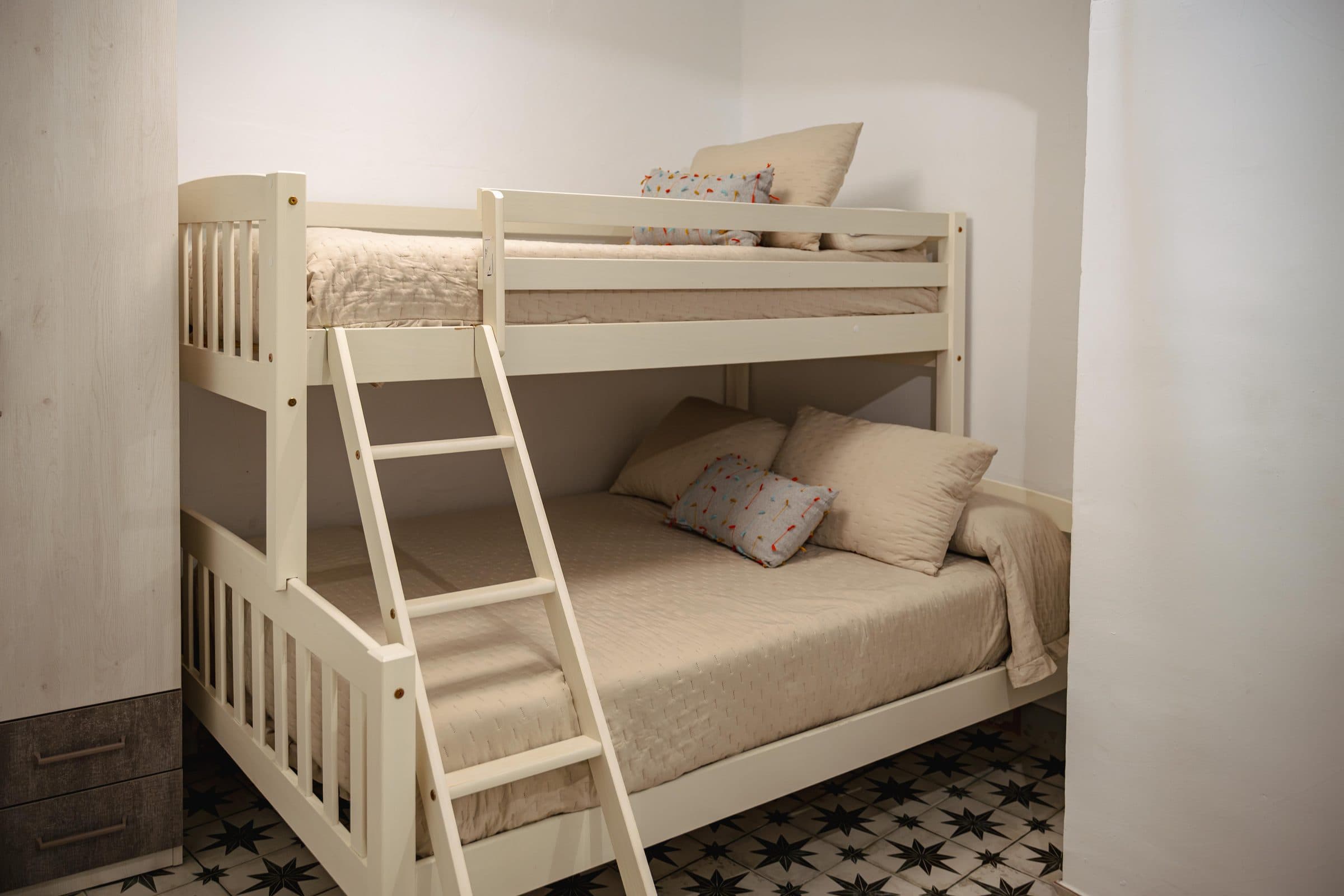 Dormitorio con litera de madera blanca y suelo hidráulico, en Casa Cuadra, en Albondón