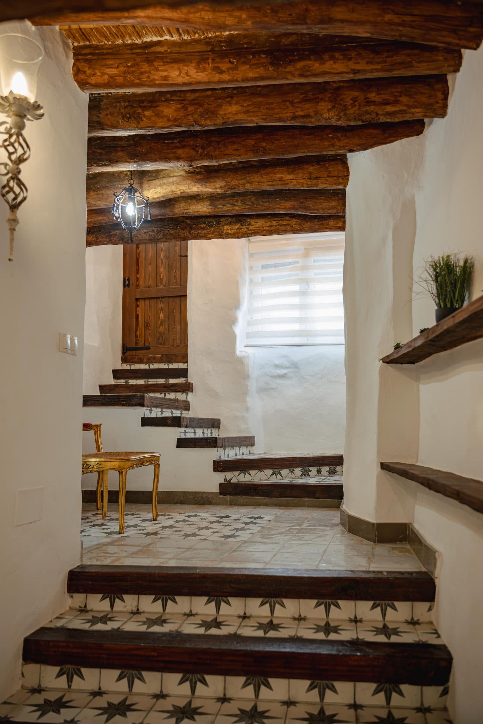 Escalera con peldaños de azulejo bajo las vigas de madera, en Casa Cuadra, en Albondón