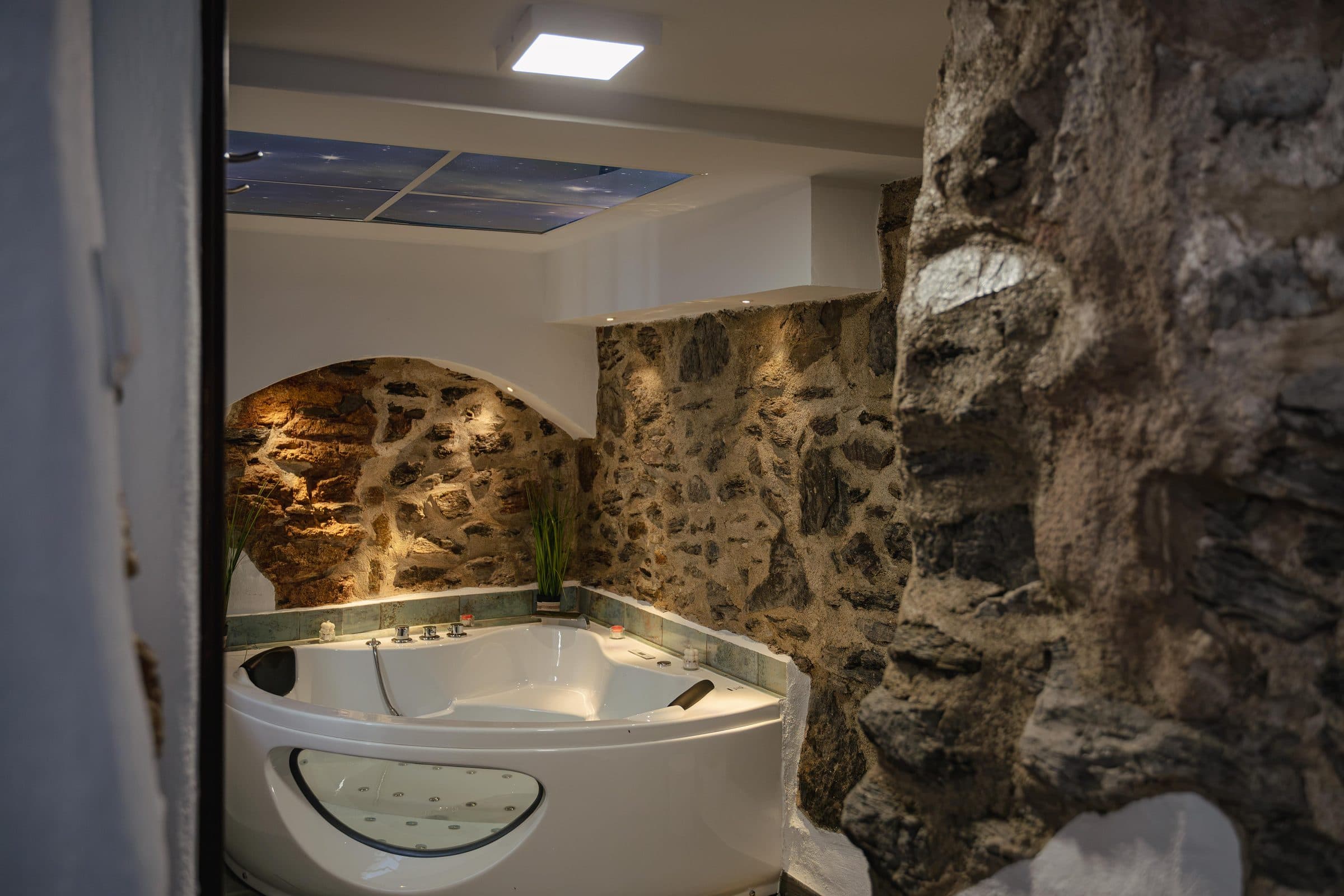 Jacuzzi con el techo iluminado y el muro de piedra original, en Casa Cuadra, en Albondón