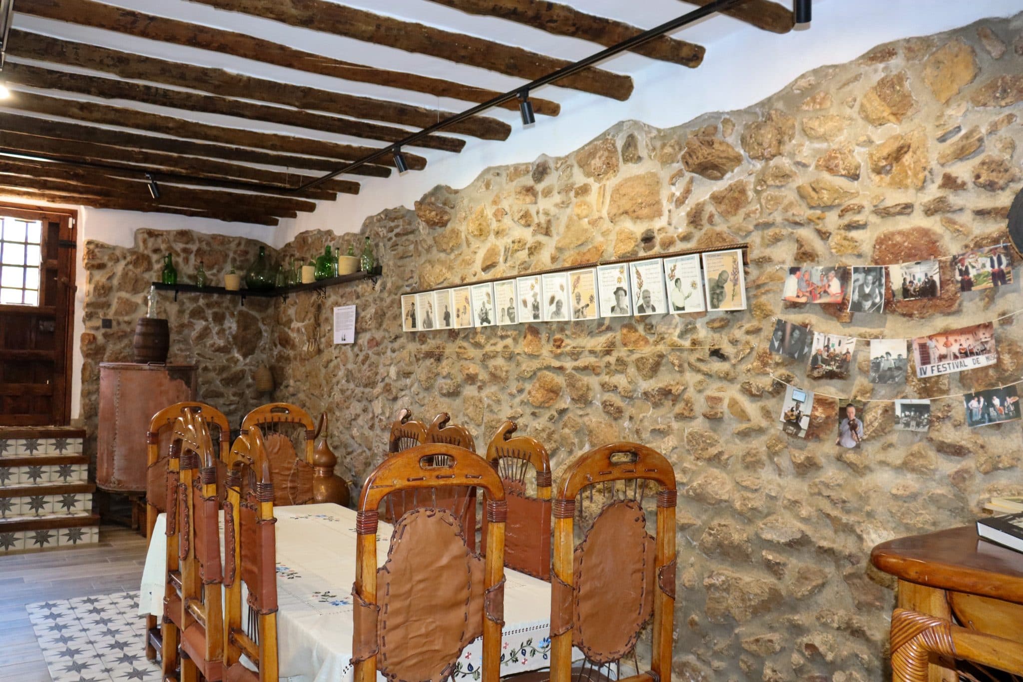 Comedor junto al muro de piedra con los retratos de los trovadores, en la Casa Museo del Trovo y Aguardiente de Murtas