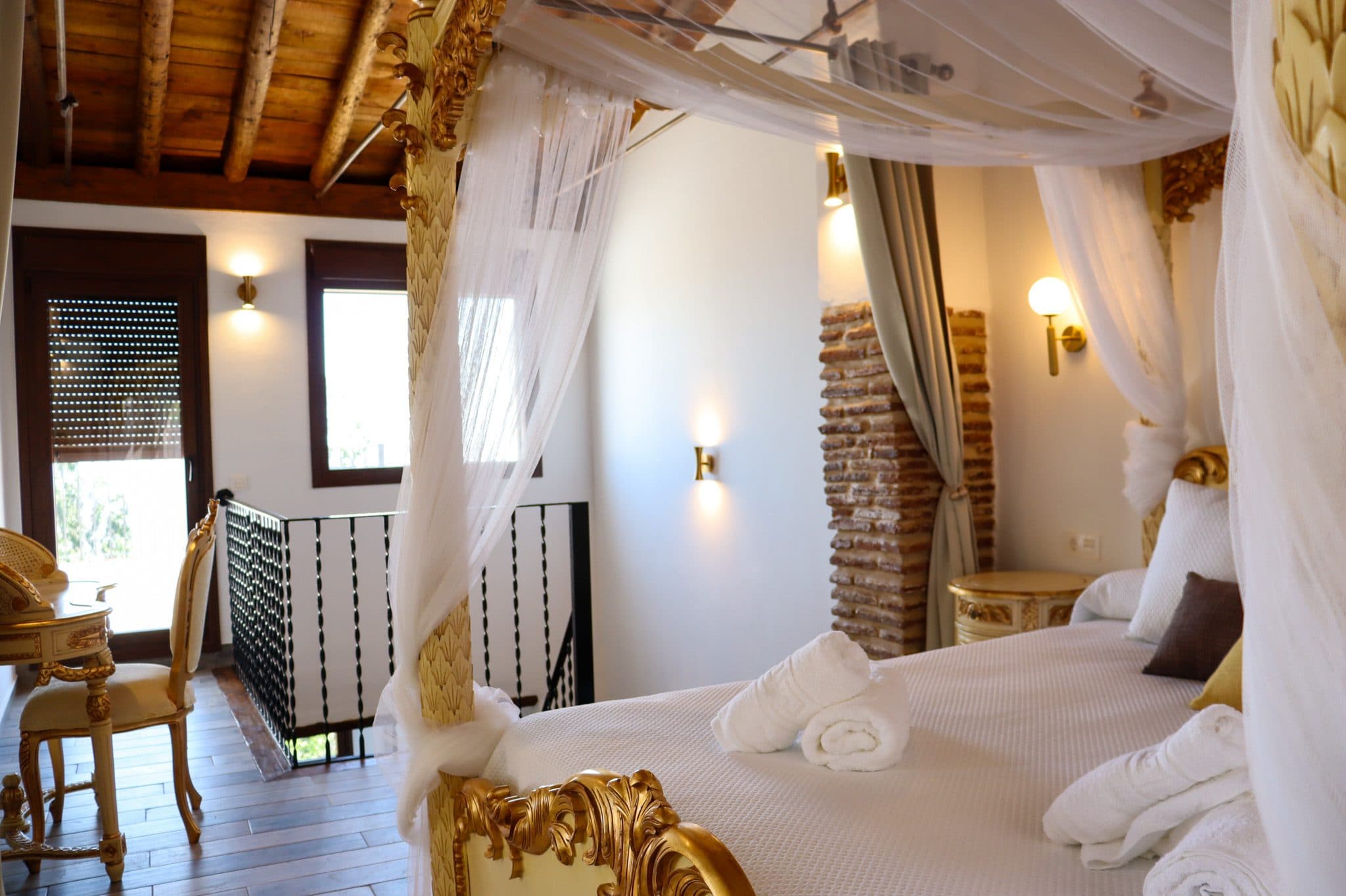 Suite del torreón, con cama de dosel bajo vigas de madera y balcón al valle, en la Casa Museo del Trovo y Aguardiente de Murtas