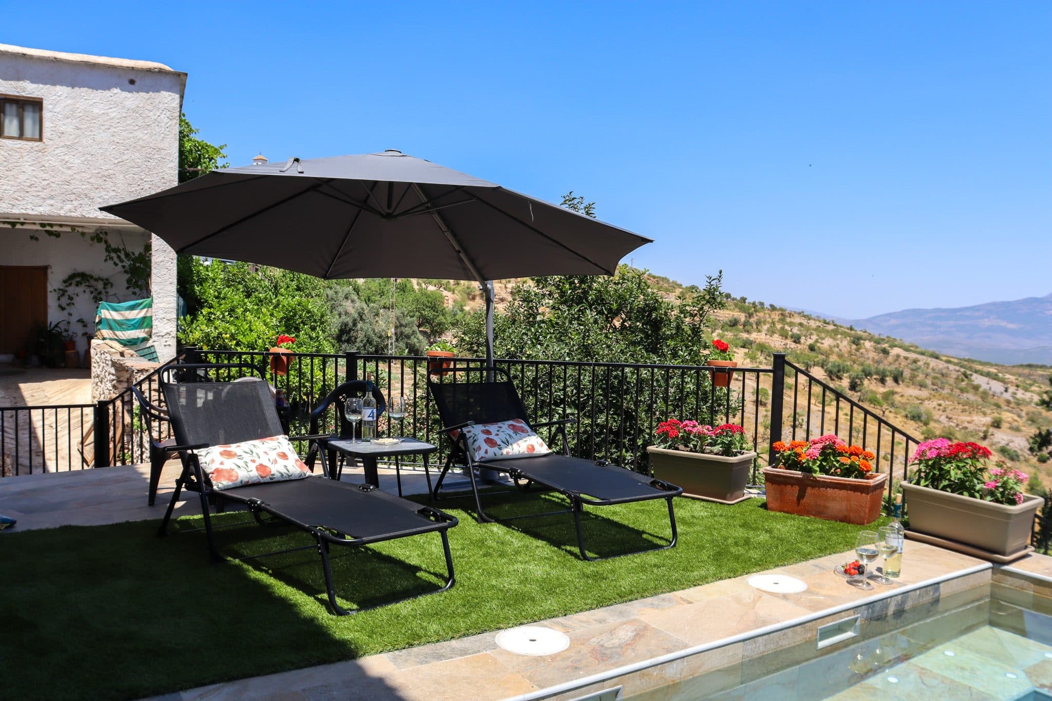 Terraza con tumbonas y geranios junto a la piscina, sobre el valle, en la Casa Museo del Trovo y Aguardiente de Murtas