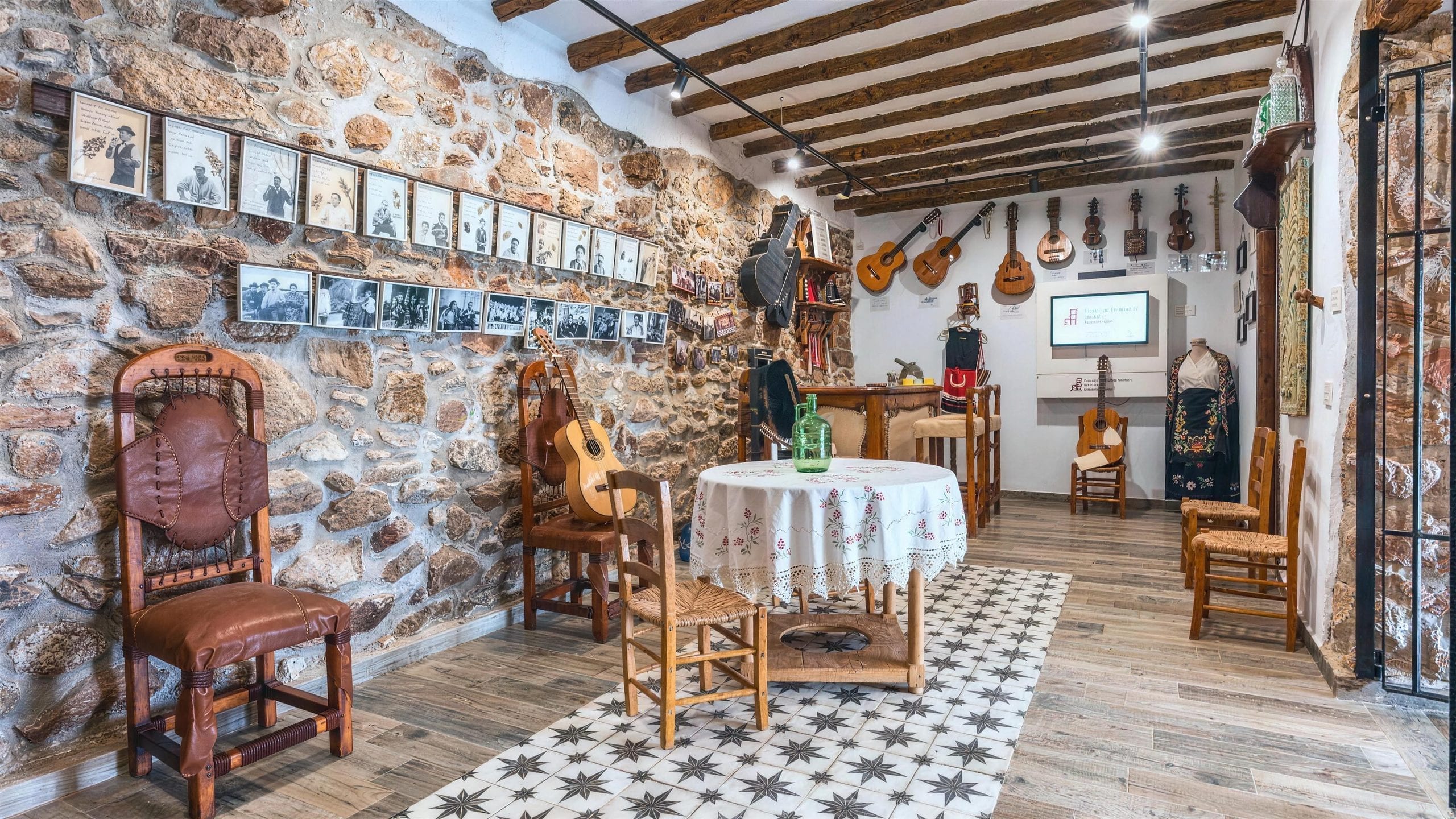 Sala del museo del trovo, con los retratos de los trovadores y las guitarras colgadas del muro de piedra, en la Casa Museo del Trovo y Aguardiente de Murtas