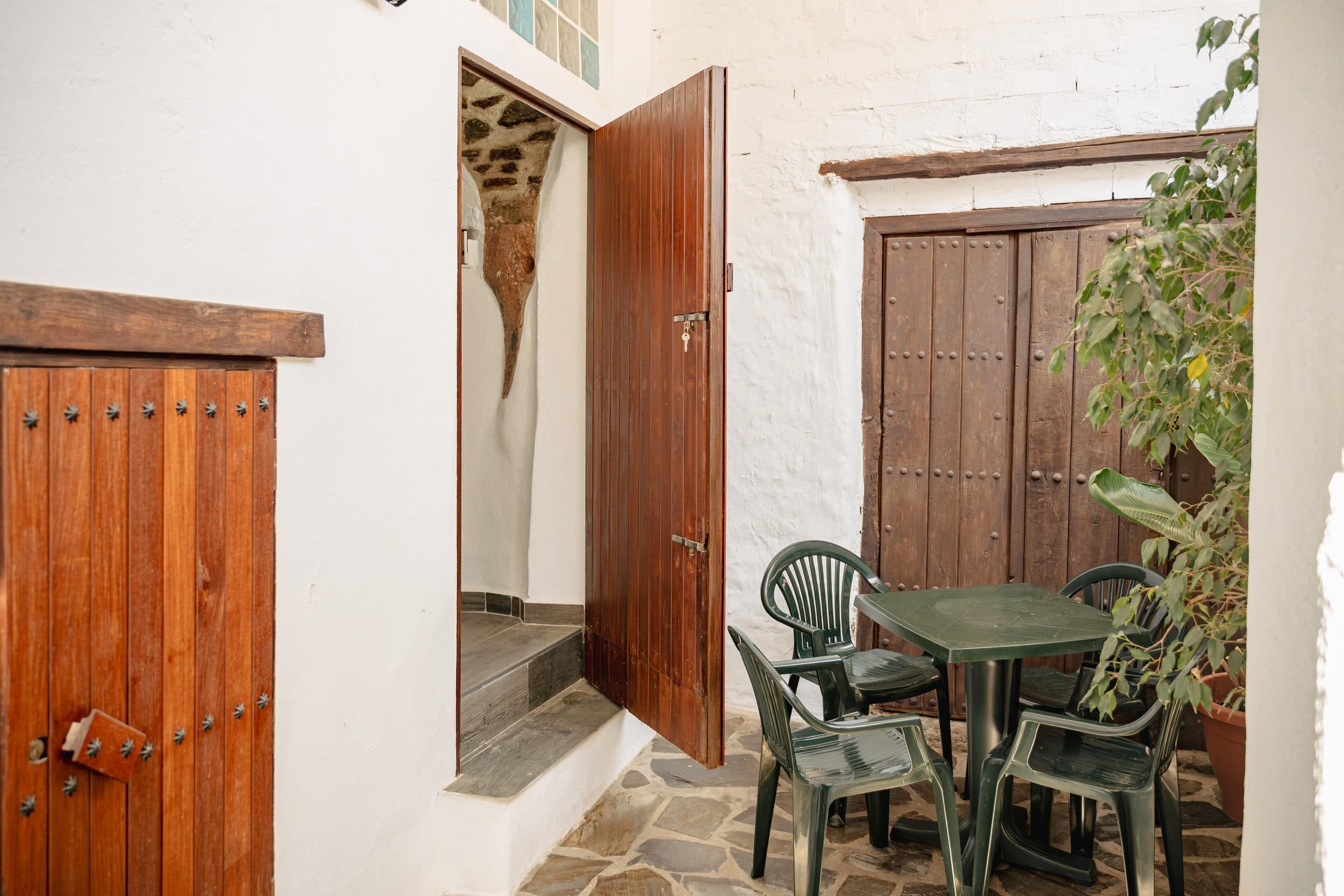 Patio de entrada con portones de madera y mesa a la sombra, en Casa Cuadra, en Albondón