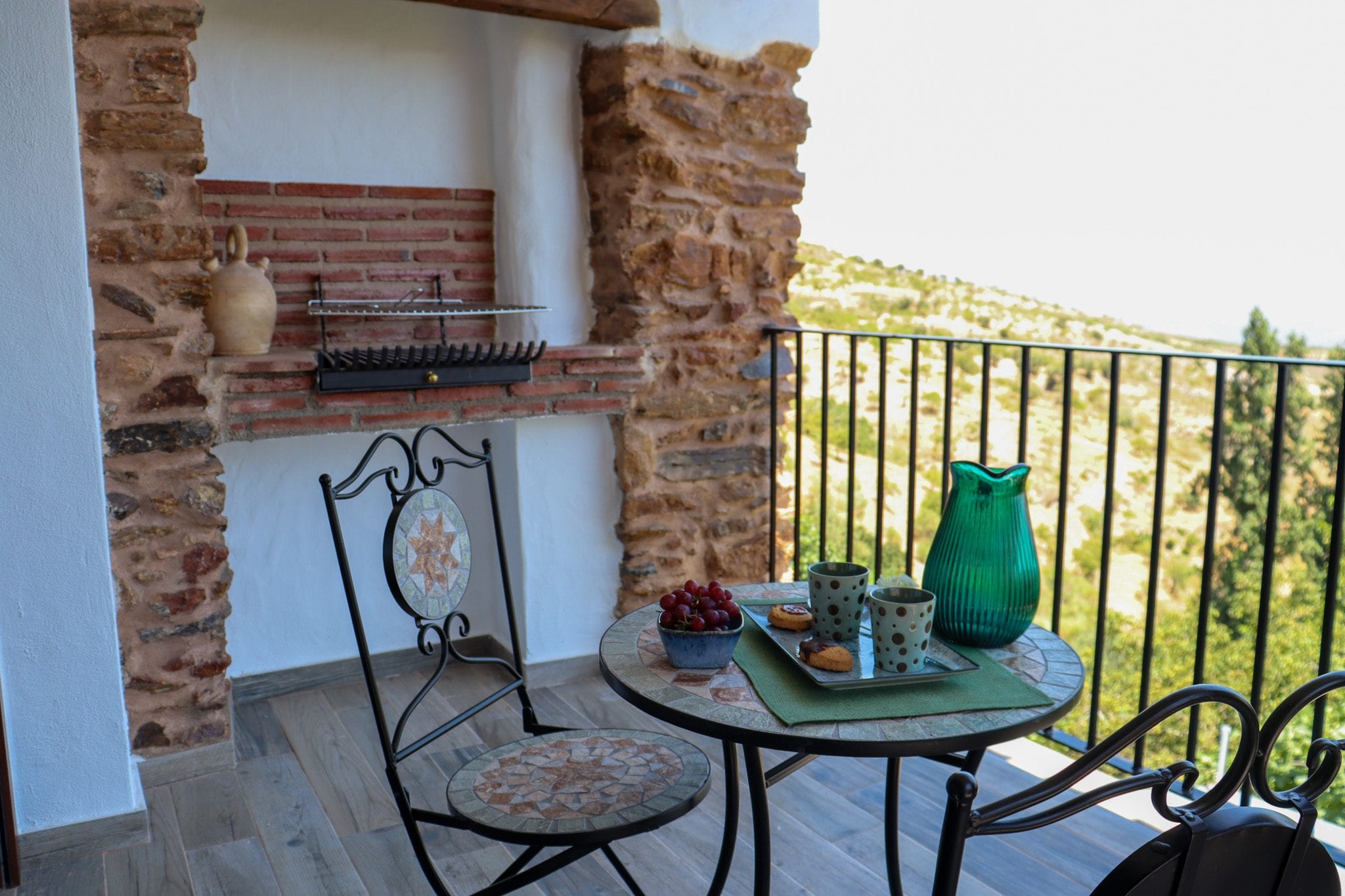 Rincón de la terraza bajo el arco de ladrillo, con mesa de forja y vistas al valle, en la Casa Museo del Trovo y Aguardiente de Murtas